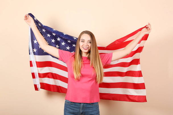 Beautiful young girl holding the flag of America on a colored background. - Foto, imagen