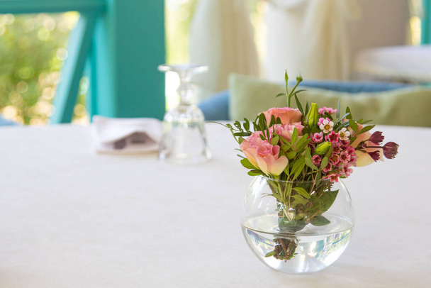 Samenstelling van bloemen in een vaas op een witte tafel. Botanie. Het concept van landschapsarchitectuur in cafés en restaurants. - Foto, afbeelding