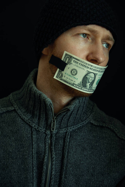Image conceptuelle de corruption et de corruption. Silencieux pour de l'argent. Portrait d'homme avec sa bouche fermée avec un billet d'un dollar
.  - Photo, image