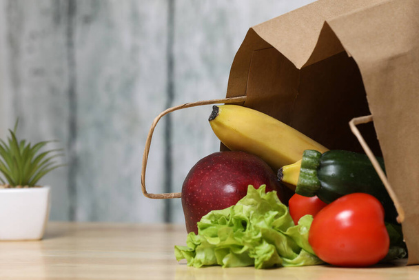 食料品の買い物袋。木の背景に野菜とリサイクル紙のショッピングバッグ。エコ製品。野菜だ。サラダ - 写真・画像