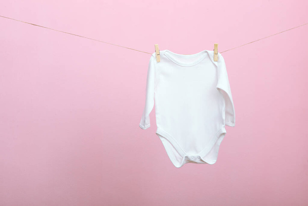 Ropa de bebé en una cuerda sobre un fondo de color. El concepto de lavar la ropa del bebé
. - Foto, imagen