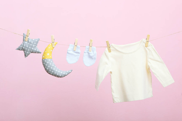 Baby clothes on a rope on a colored background. The concept of washing baby clothes. - Photo, Image