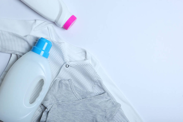 Dětské oblečení a detergenty na barevném pozadí horní pohled. Koncept praní dětských šatů. - Fotografie, Obrázek
