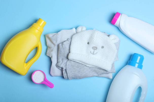 Babykleidung und Waschmittel auf farbigem Hintergrund von oben. Das Konzept der Babywäsche. - Foto, Bild