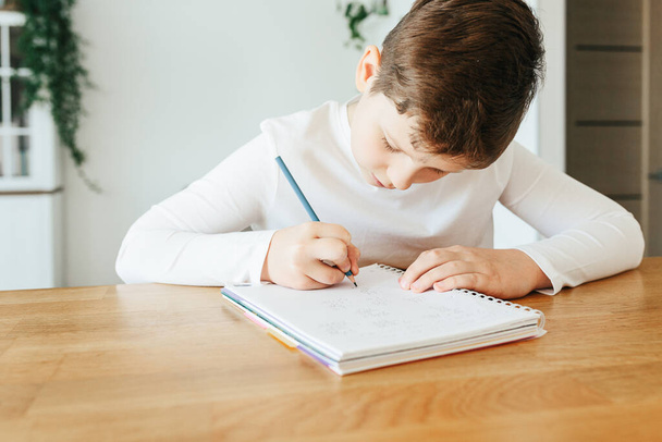 Hard-working school kid boy making homework math during quarantine time from corona pandemic disease. Education and distance learning for kids. Homeschooling during quarantine. Homeschooling concept - Foto, Imagem