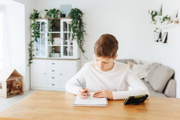 Hard-working school kid boy making homework math during quarantine time from corona pandemic disease. Education and distance learning for kids. Homeschooling during quarantine. Homeschooling concept - Foto, Imagen