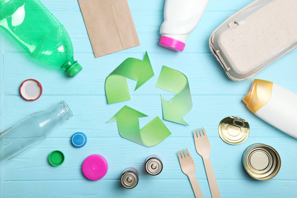 Διαφορετικοί τύποι σκουπιδιών και πινακίδα ανακύκλωσης σε έγχρωμο φόντο πάνω όψη. Η έννοια της διατήρησης της φύσης, του διαχωρισμού και της διαλογής των απορριμμάτων. - Φωτογραφία, εικόνα