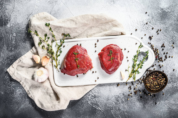 Marmor Rinderfilet. rohes Filet Mignon Steak auf einem weißen Schneidebrett. grauer Hintergrund. Ansicht von oben. - Foto, Bild