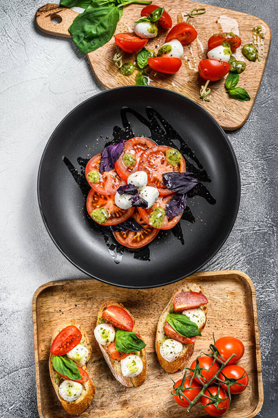 Caprese salad, skewers canapes and bruschettes with cherry tomatoes, mozzarella and Basil. gray background. top view. - Fotografie, Obrázek