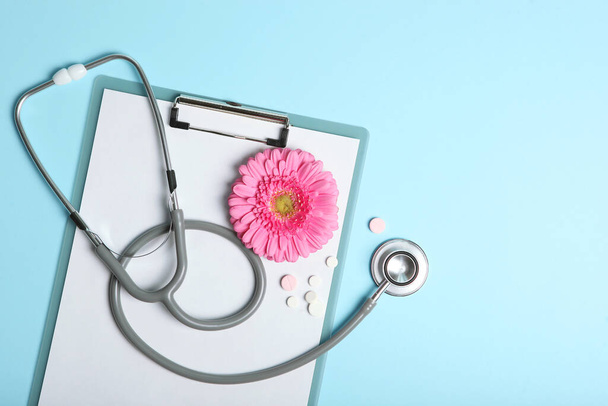 Gerbera und Stethoskop auf farbigem Hintergrund von oben. Symbol für Frauengesundheit und Frauenheilkunde. - Foto, Bild