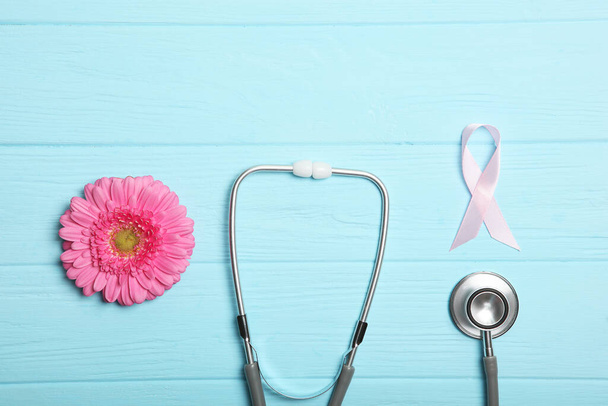 różowa wstążka, gerbera i stetoskop na kolorowym tle widok z góry. Symbol kobiecego raka. Świadomość nowotworów u kobiet - Zdjęcie, obraz