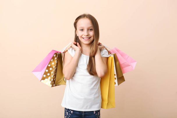 色の背景で買い物のための袋を持つ美しい笑顔の女の子。子供の買い物の概念. - 写真・画像