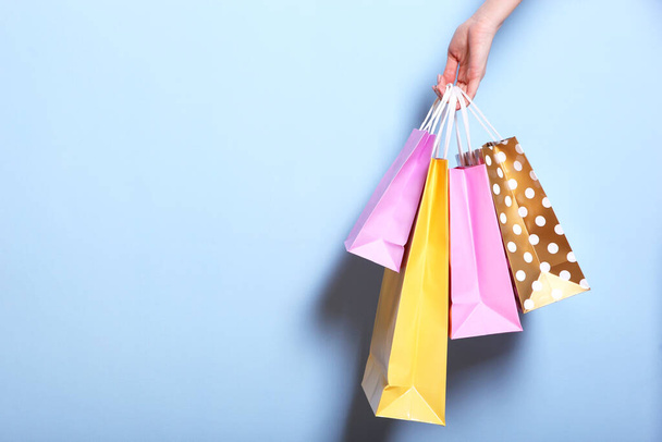 bags for shopping in hand on a colored background. Paper bags for shopping. A place to insert text, minimalism. - Photo, Image