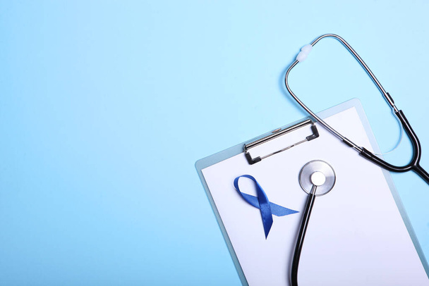 Modrá stuha na barevném pozadí horní pohled. Mužská rakovina, mužské zdraví. Mezinárodní symbol rakoviny u mužů. - Fotografie, Obrázek