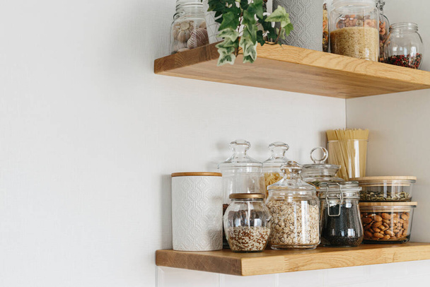 Various cereals and seeds in glass jars on the shelves in the kitchen. Kitchen interior ideas. Eco friendly kitchen, zero waste home concept - Foto, afbeelding