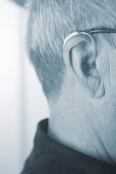 Caucasian white old aged man wearing modern digital hearing aid in ear with grey hair. - Photo, Image