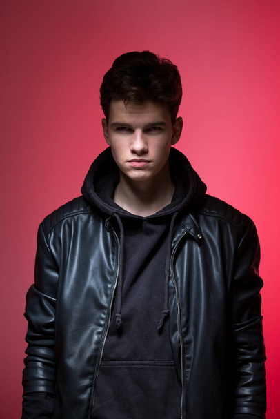 Cute brutal man in black leather jacket model style. Portrait of a handsome guy on pink studio background. Man In Black Jacket. Young Fashion Man In Leather Jacket on a pink background. - Foto, imagen