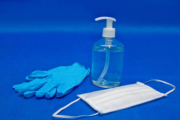 Fertőtlenítő palack, latex kesztyű, arcpakolás kék alapon, a koronavírus megelőzésére - Fotó, kép
