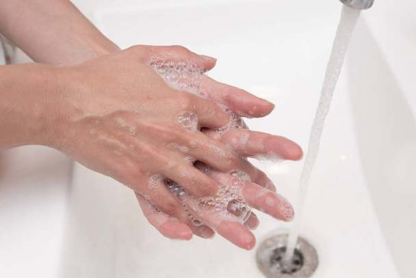 latin woman washing her hands with soap at home - Foto, Imagen
