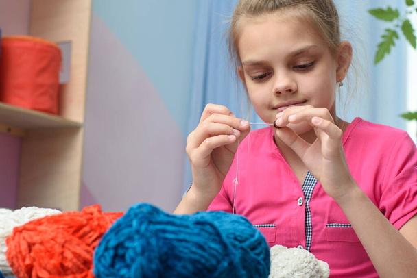 Meisje strung een kraal op een naald borduren speelgoed - Foto, afbeelding