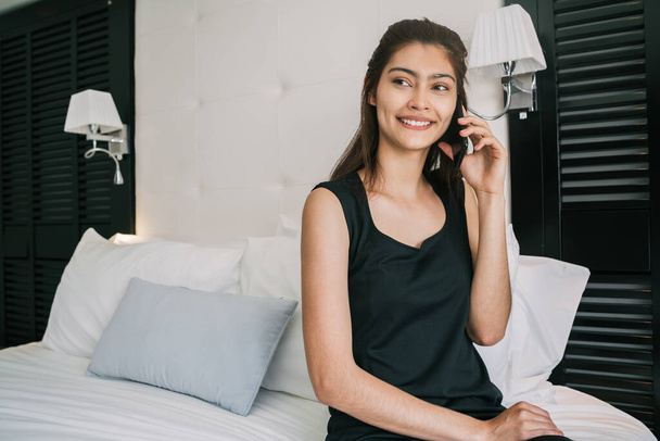 Portrait of young businesswoman talking on the phone at the hotel room. Business travel concept. - Фото, изображение