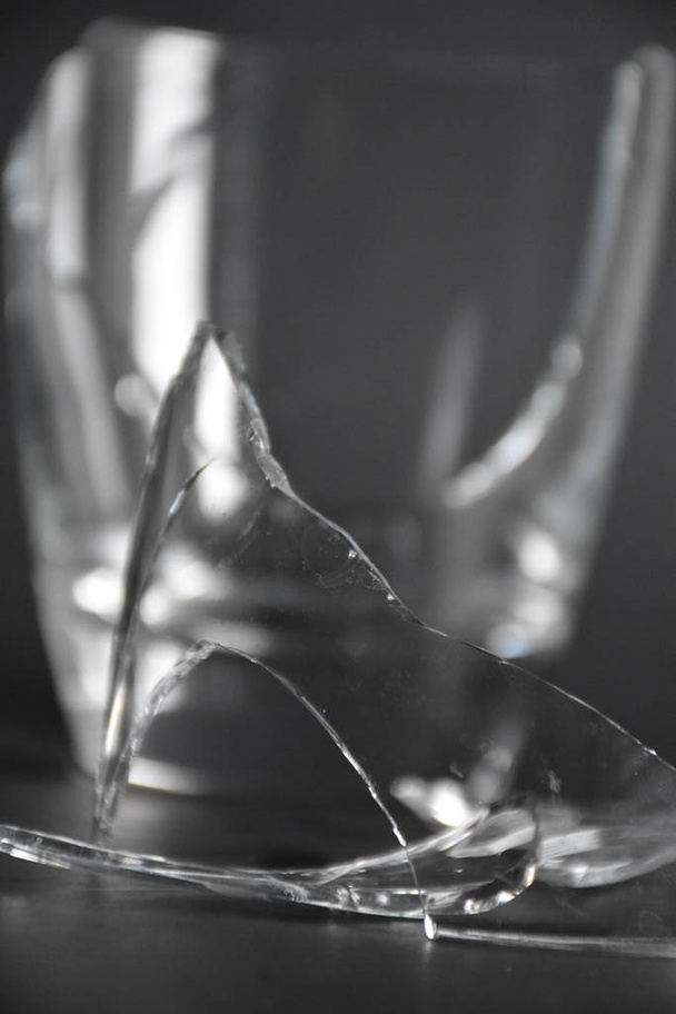 gebroken glas met stukken en fragmenten op donker zwarte achtergrond, concept van gevaar - Foto, afbeelding