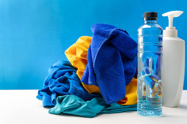 Bouteilles en plastique de produits de nettoyage fixées avec des vêtements de pile sur fond bleu de table blanc
 - Photo, image