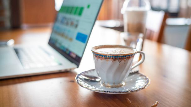 Heißes Aroma Cappuccino Kaffeetasse auf Holztisch Arbeit von zu Hause mit Laptop, Home Business WFH-Konzept - Foto, Bild