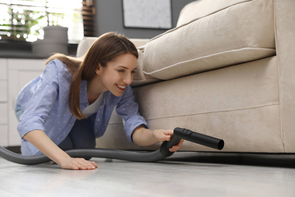 Young woman using vacuum cleaner at home - Foto, Bild