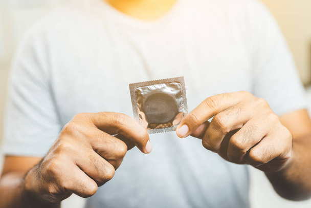 Mužská ruka držící kondom. Bezpečný sexuální koncept. - Fotografie, Obrázek