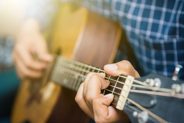 close-up van jonge man spelen gitaar - Foto, afbeelding