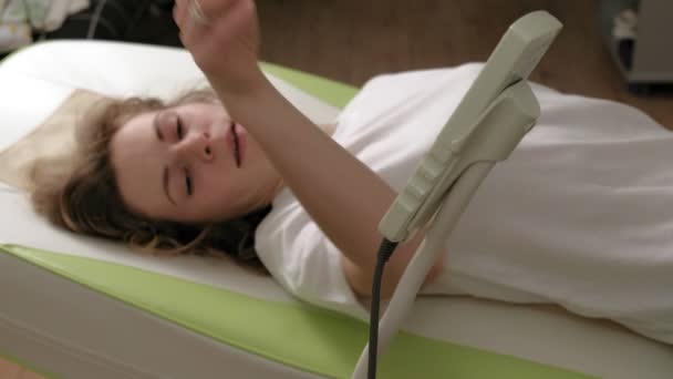Egy nő fekszik egy masszázs elektronikus ágyon.. - Felvétel, videó