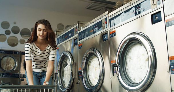 Cheerful Caucasian young beautiful woman having fun and laughing as throwing clothes from basket at laundry service. - Photo, image