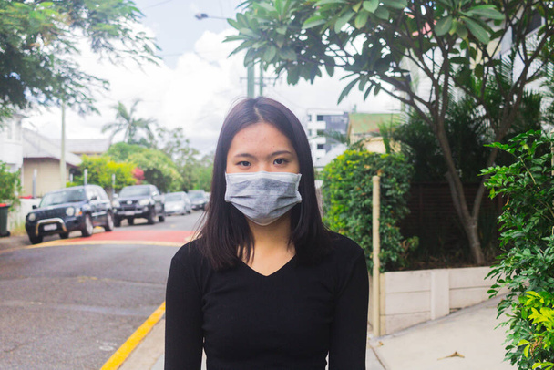 Пандемія Коронавірус Азіатська дівчинка на вулицях міста, одягнена в маску обличчя, яка захищає від поширення хвороби Коронавіруса 2019 року.. - Фото, зображення