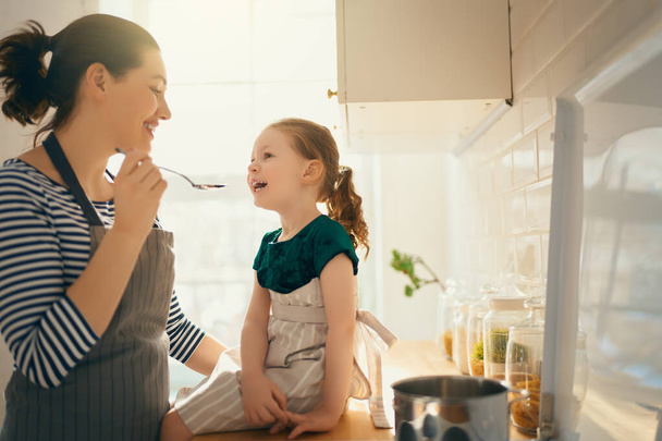 Healthy food at home. Happy family in the kitchen. Mother and child daughter are preparing proper meal.  - Valokuva, kuva