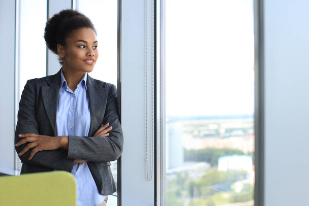 Attractive african american business woman looking at camera and smiling while standing in the office - Fotoğraf, Görsel