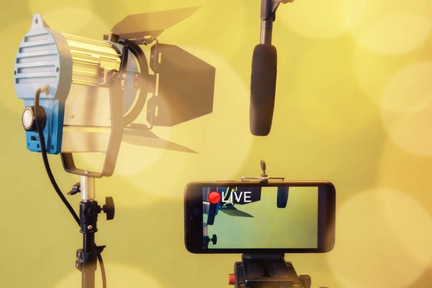 Live Stream Video Multimedia Concept. smartphone , microphone and reflectors on the Yellow background - Photo, Image