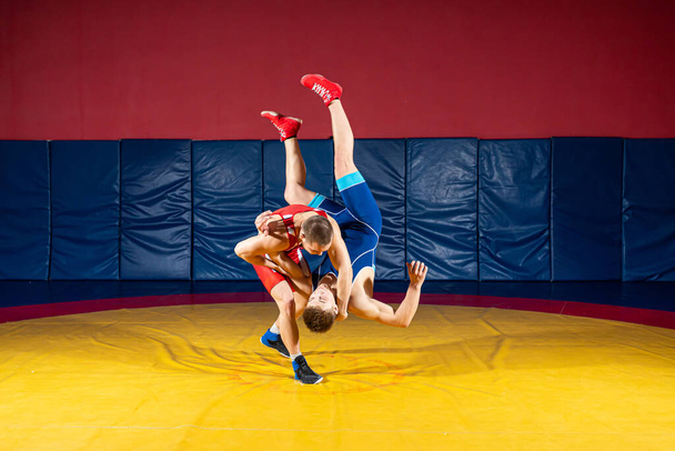 A tisztességes birkózás fogalma. Két greco-római birkózó sportruhában feldob egy birkózó szőnyeget a tornateremben.A férfi birkózás és ellenállás fogalma - Fotó, kép
