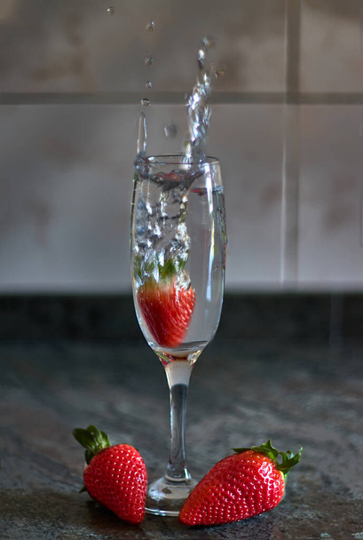 Strawberry falling into a glass and splashing water - Photo, Image