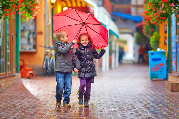 niños felices caminando bajo la lluvia en la calle colorida
 - Foto, Imagen