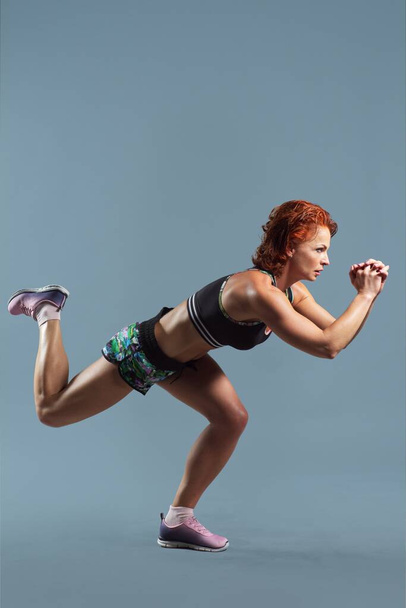 Mature athletic redhead woman in sportswear t-shirt and shorts doing fitness exercises - Фото, зображення