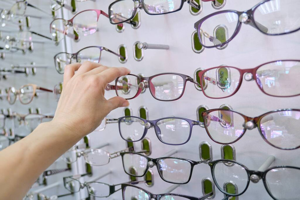 Showcase with glasses in the store, hand choosing glasses - Photo, image