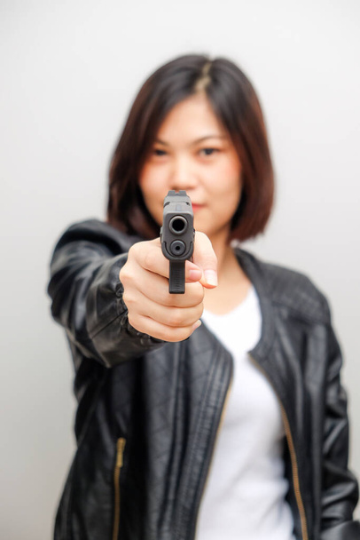 Black shirt women aiming gun to audience on white background, Defense personal trainning - Photo, Image