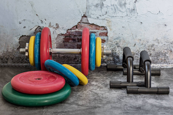 Επαγγελματικά αλτήρες, πολύχρωμα πιάτα βάρους και push-up στάσεις σε ένα vintage φόντο. Αθλητικός εξοπλισμός. Υγιής τρόπος ζωής - Φωτογραφία, εικόνα