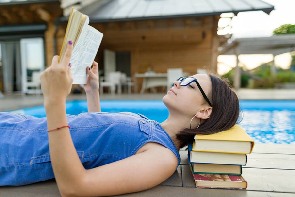 Menina adolescente inteligente em óculos livro de leitura, adolescente perto de casa
 - Foto, Imagem