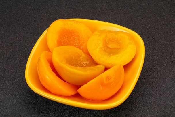 Маринованные персиковые фрукты в миске с сиропом - Фото, изображение