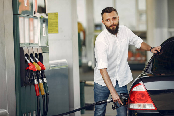 Handsome man pours gasoline into tank of car - Zdjęcie, obraz