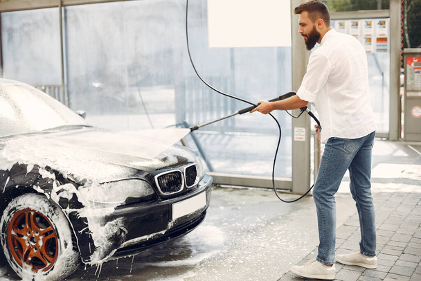 Handsomen man in a white shirt washing his car - Photo, image