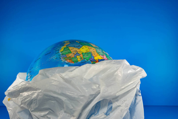 Grocery Plastic with earth inside with blue background. Earth is being destroyed because of too much garbage like plastic - Foto, immagini