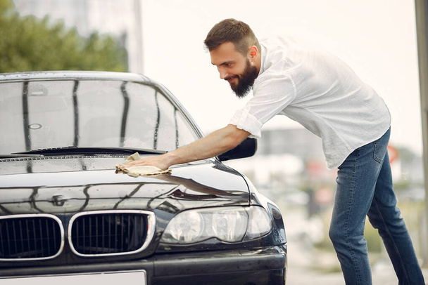 Man in a white shirt wipes a car in a car wash - Φωτογραφία, εικόνα